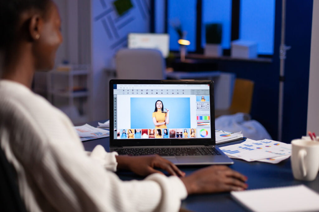 A person using a laptop with an image editing program displayed on the screen.